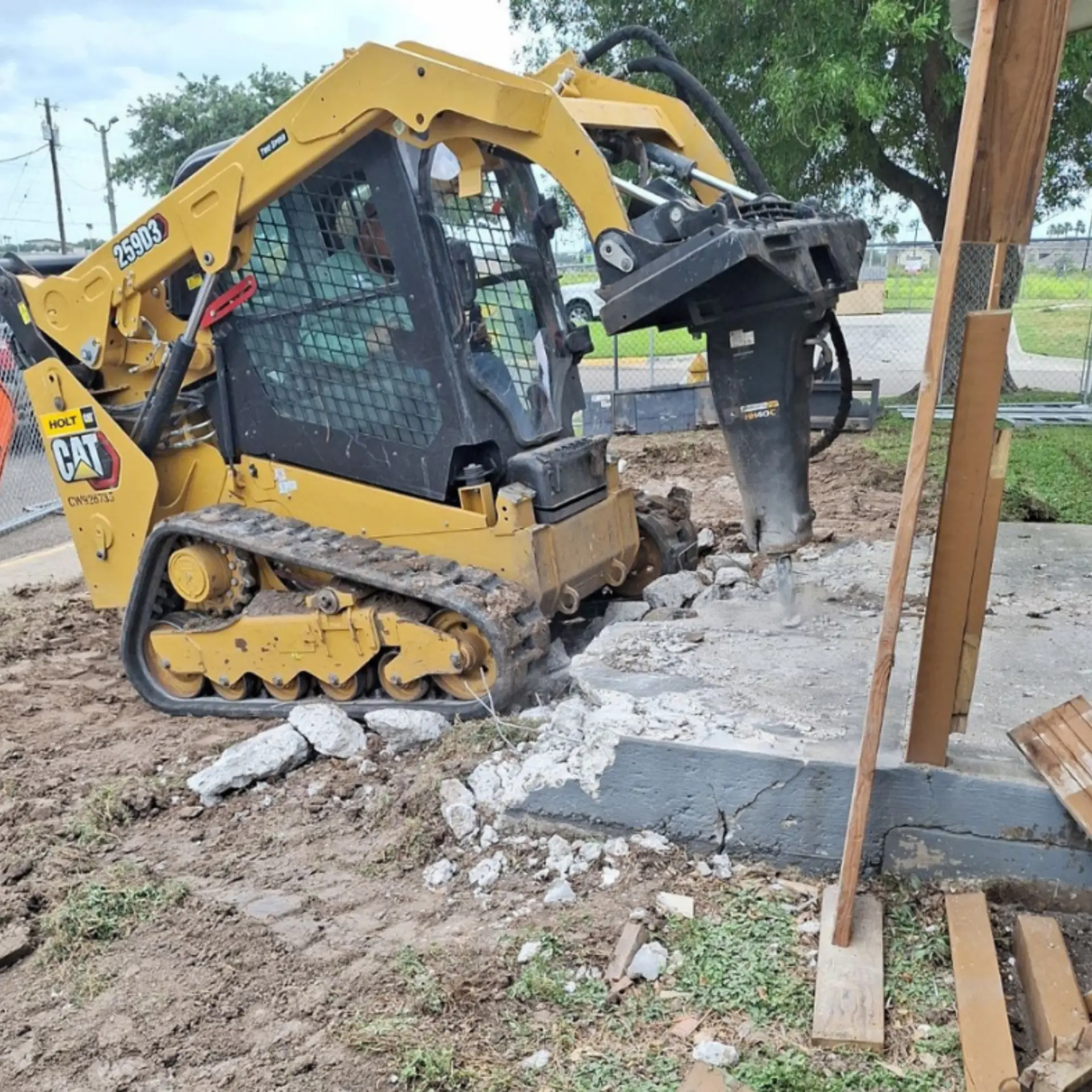 Hydraulic breaker attachment working a concrete slab on a foundation job