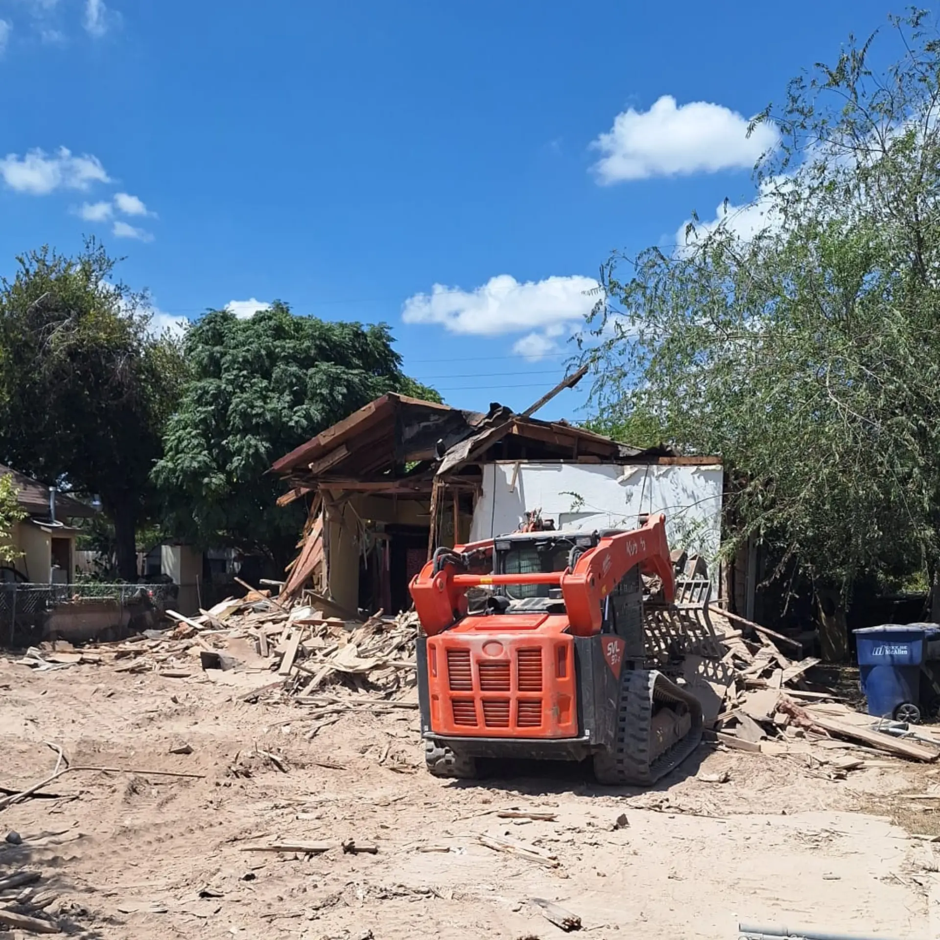 Track loader clearing debris after a house teardown