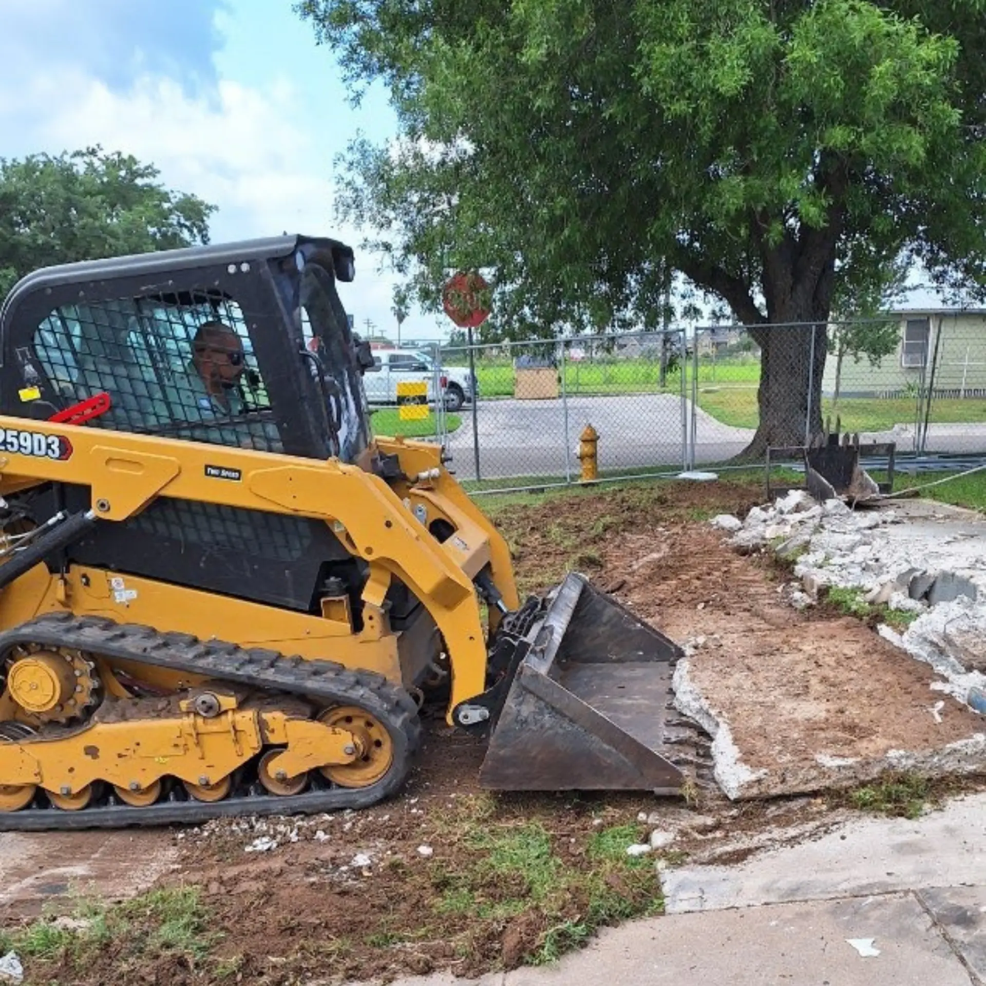 Track loader tearing out an old concrete sidewalk in a residential area