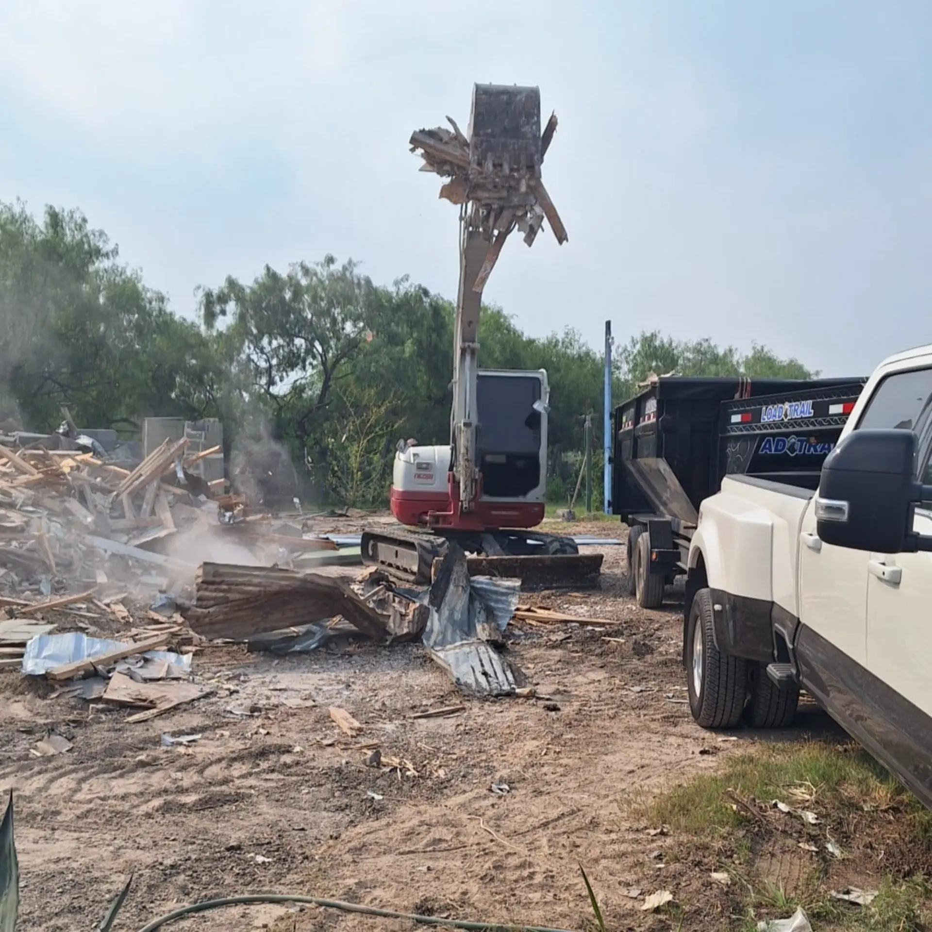 Excavator loading demolition debris into a dump trailer for hauling