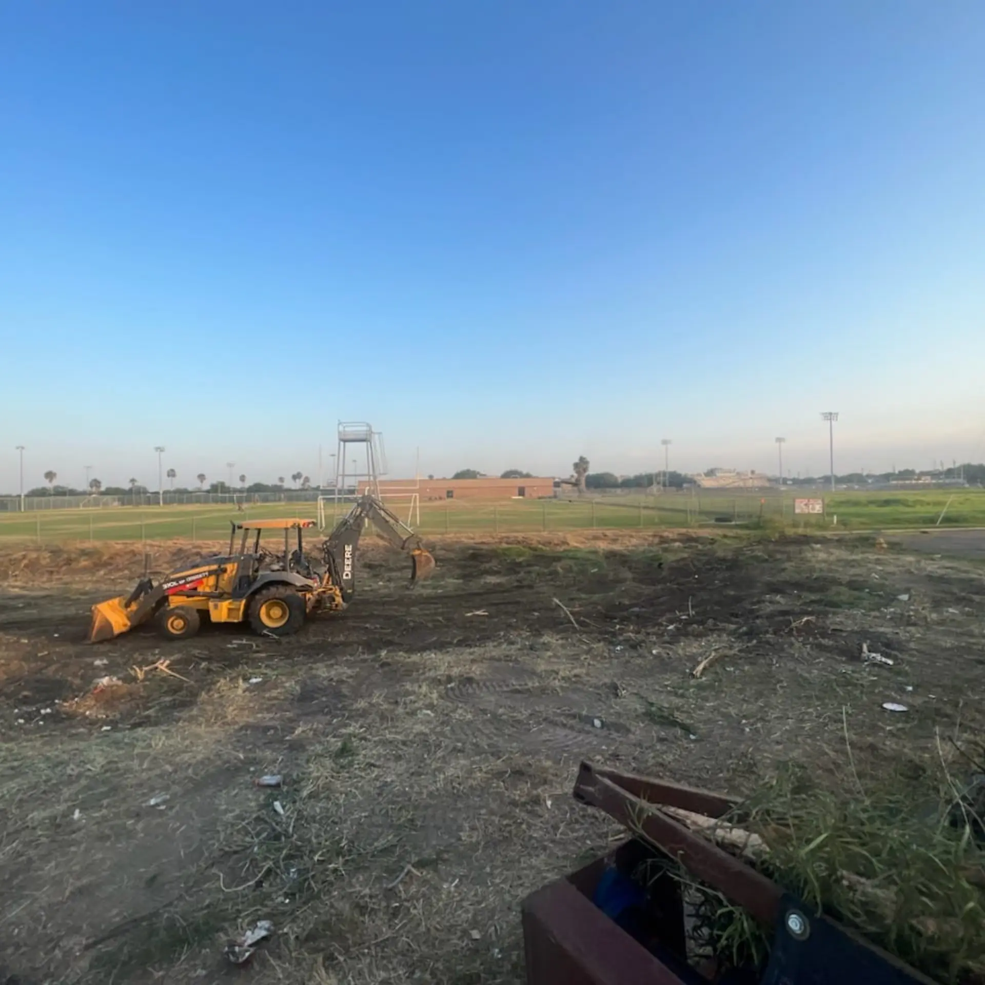 Backhoe clearing brush from a large open field